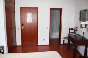 a room with a bed, chair and a television at Hotel Dona Leonor in Caldas da Rainha