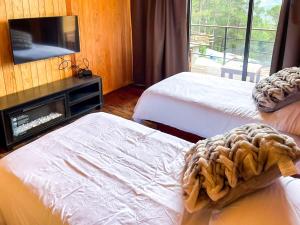 a room with two beds and a tv on a wall at Alto de la Sierra by Rotamundos in El Pacífico