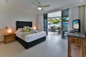 a bedroom with a bed and a television and a balcony at Frangipani Apartments on Hamilton Island by HIHA in Hamilton Island