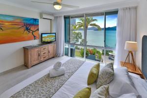 - un salon avec un lit et une grande fenêtre dans l'établissement Frangipani Apartments on Hamilton Island by HIHA, à Île Hamilton