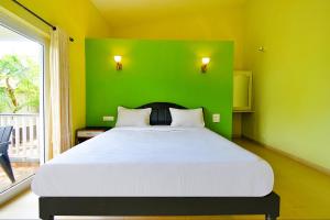 a bedroom with a green wall and a bed at FabEscape Vagator Retreat Resort With Swimming Pool in Goa Velha