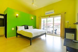 a green bedroom with a bed and a large window at FabEscape Vagator Retreat Resort With Swimming Pool in Goa Velha