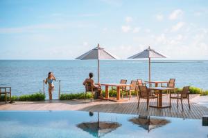 two people sitting at a table next to the ocean at Rocky's Boutique Resort - Veranda Collection Samui in Lamai