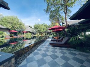 een resort met een zwembad met tafels en parasols bij Na Mantra Resort in Chiang Mai