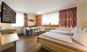 a hotel room with a bed and a dining room at Pension Schenkenfelder in Bad Häring