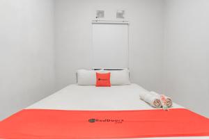 a bed with a red and white blanket on it at RedDoorz near Exit Toll Pasteur 4 in Bandung