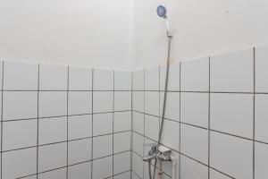 バンドンにあるRedDoorz near Exit Toll Pasteur 4の白いタイルの壁にシャワーヘッド付きのシャワーが備わります。