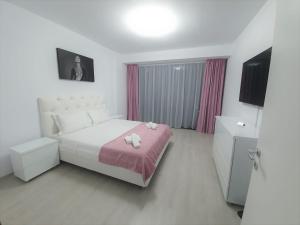 ein Schlafzimmer mit einem großen weißen Bett mit rosa Bettwäsche in der Unterkunft AP RELAX Tulcea in Tulcea