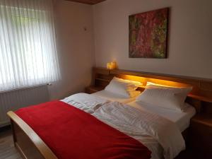a bedroom with two beds with a red blanket at Gasthof-Pension Hunaustuben in Schmallenberg