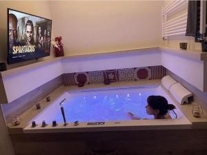 a woman in a jacuzzi tub with a tv at MAD SUITES & APARTMENTS in Bernalda