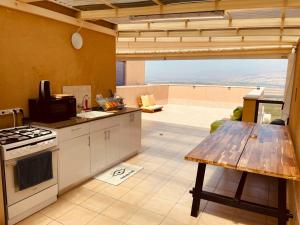 a kitchen with a stove and a table with a view at Nilis vila הווילה של נילי in Mishmār Hāyardin