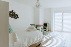 a white bedroom with a bed and a table at Skip Skop in Paternoster