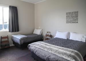 A bed or beds in a room at Hokitika Pioneer Hotel