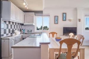 cocina con armarios blancos, mesa y sillas en Apartamento Palmeras de Benavista, en Estepona