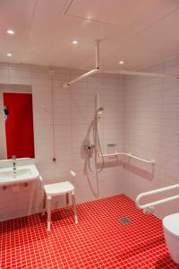 a bathroom with a shower and a red floor at havenhostel Cuxhaven in Cuxhaven