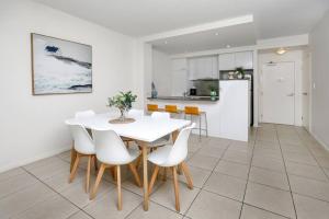 a kitchen and dining room with a white table and chairs at Pool View City Centre Apartment 206 in Cairns