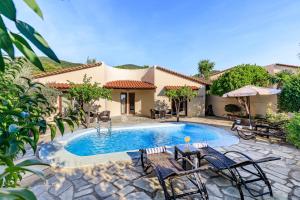a swimming pool with chairs and a house at Skopelos Holidays Hotel & Spa in Skopelos Town