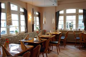 um restaurante com mesas e cadeiras de madeira e janelas em Hotel Rebstöckle em Hagnau