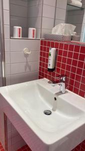 a white sink in a bathroom with red tiles at havenhostel Cuxhaven in Cuxhaven