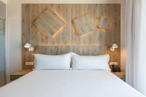 a bedroom with a white bed and a wooden wall at Senator Gandia in Gandía