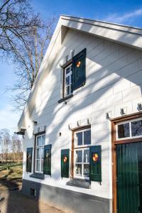 una casa bianca con porte e finestre verdi di Herberg de Pas a Haarle