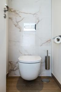 a white toilet in a bathroom with marble walls at Senator Gandia in Gandía