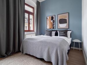 Un dormitorio con una cama con paredes azules y una ventana. en Limehome Dresden Hoyerswerdaerstraße, en Dresden