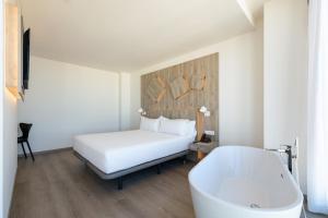 a bedroom with a white bed and a bath tub at Senator Gandia in Gandía