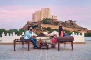 Alila Fort Bishangarh Jaipur - A Hyatt Brand في جايبور: يجلس شخصان على طاولة مع قلعة في الخلفية
