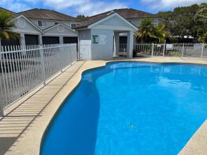 a blue swimming pool in front of a house at The Beach House # 15 Paradise Waters in Coffs Harbour