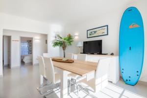a dining room with a table and a surfboard on the wall at Beautiful Seaview 2 Bedroom Apartment in Luz