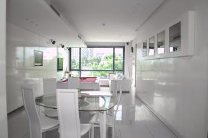 Johannesburg的住宿－Stunning 2 Bedroom Apartment，一间设有玻璃桌和白色椅子的用餐室