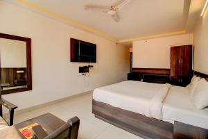 a bedroom with a bed and a table and a tv at FabHotel PS Grand in Lucknow