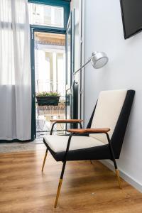 a chair sitting in a room with a lamp at Maria da Sé Historic House in Porto