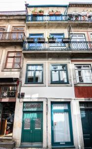a tall building with green doors and windows at Maria da Sé Historic House in Porto