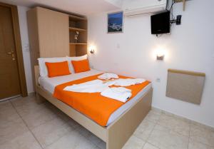 a bedroom with a bed with orange and white pillows at Sunset Studios in Skala Marion
