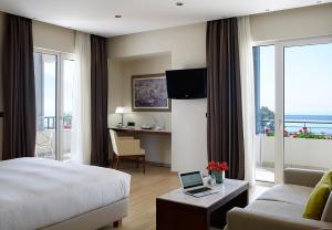 a hotel room with a bed, tv and a desk at Pharae Palace in Kalamata