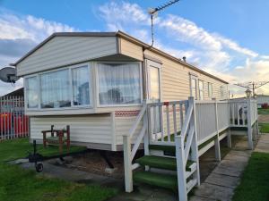 a tiny house with a porch and stairs at 6 Berth Kingfisher (Firs) in Ingoldmells