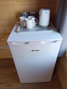 Un refrigerador blanco con tres tazas encima. en Cosy Cabin en Stock