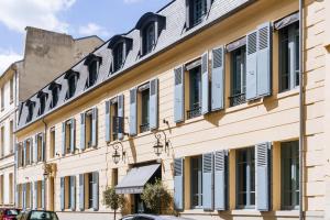 un edificio con ventanas y persianas en una calle en Hôtel du Jeu de Paume, en Versalles