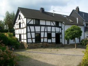 ein altes weißes und schwarzes Haus mit Garten in der Unterkunft Authentiek Eifelhuis in Hecken