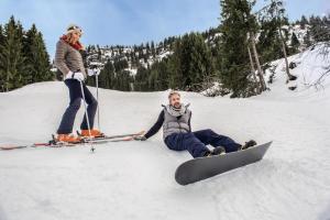 a man and a woman sitting in the snow with a snowboard at Belambra Clubs Praz-sur-Arly - L'Alisier in Praz-sur-Arly