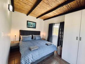 ein Schlafzimmer mit einem Bett mit einer blauen Bettdecke in der Unterkunft Heron Cottage - Living The Breede in Malgas