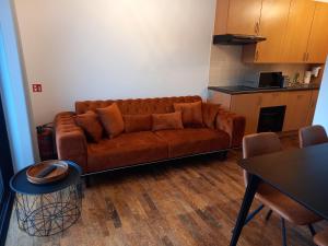 ein Wohnzimmer mit einem braunen Sofa und einem Tisch in der Unterkunft appartement zee zon en zwem in Bredene-aan-Zee