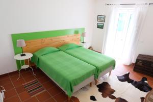 ein Schlafzimmer mit einem Bett mit grüner Decke in der Unterkunft Casa da Malta in Livramento
