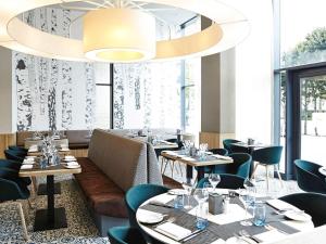 ロンドンにあるノボテル ロンドン ウェンブリーのテーブルと椅子、大きなシャンデリアのあるレストラン