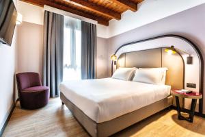 シレーアにあるティツィアーノ イン ホテル トレヴィーゾのベッドと椅子付きのホテルルーム