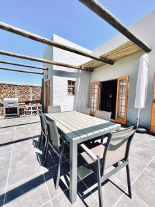 y un patio con mesa de comedor y sillas. en Owl Cottage - Living The Breede, en Malgas