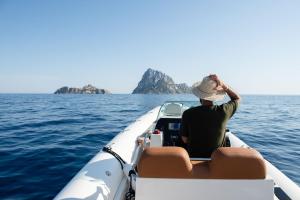 Un uomo seduto in una barca in acqua di Petunia Ibiza, a Beaumier hotel a Cala Vadella