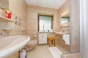 Un baño con bañera, inodoro y lavabo. en Ferienwohnung Schmankerl, en Reit im Winkl 13 fotos más